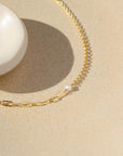 14k gold fill Emma bracelet laying on a tan plate in the sunlight.
