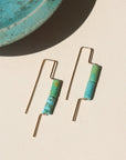 14k gold fill threaders with two turquoise tube shaped gemstones, the earrings are displayed on a cream backdrop