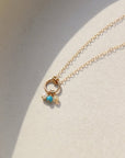 14k solid gold necklace made by Token Jewelry, featuring a simple chain and circle, with customizable birthstone charms, photographed on a white dish