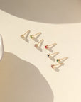 Set of gold filled birthstone prong set earrings on a beige surface with soft shadows