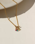 A 14k gold fill toggle necklace featuring a curb chain with four gold wire wrapped birth stones dangling from the toggle. Necklace is displayed on a cream back drop.
