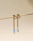 A 14k gold fill back drop with a dainty curb chain, with three opal gemstones and one mini pearl set at the bottom