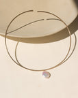 A 14k gold fill collarbone style necklace with a pearl dangling its center.