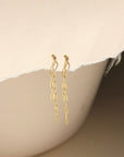A 14k gold fill small paper clip chain, dropped from a small gold ball stud, the earrings are displayed on a cream backdrop in the sunlight