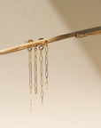 A 14k gold fill small paper clip chain, dropped from a small gold ball stud, the earrings are displayed on a cream backdrop in the sunlight