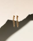 A 14k gold fill textured rolo chain dropped from a classic ball stud, displayed on a cream backdrop in the sunlight.