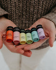 Person holding small rainbow lip balms with labels in their hands.