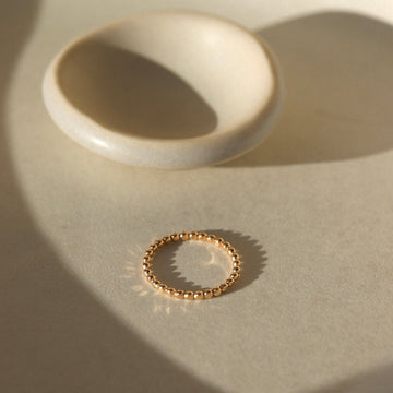 14k gold fill Sequin Ring placed on a white plate in the sunlight. This ring features our sequin band. This ring is perfect for stacking and everyday wear.