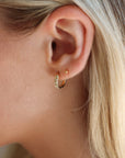 Close-up of a person wearing a gold hoop earring with blonde hair.