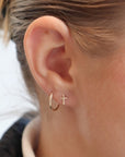 Model wearing 14k gold fill cross stud earrings. Along with the classic Goldie hoops.