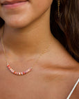 Close-up of a woman wearing a delicate necklace with beads.