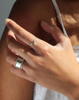 Model wearing a sterling silver ring stack. Featuring a thick sterling silver hammered band stacked between two sequin rings.