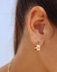 Brunette model wearing the laine hoops. Hoops feature a hammered gold wire with a textured edge.