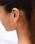 Brunette model wear the medium nines. This earring features a small gold wire that is rounded into a nine.
