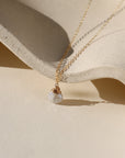 Delicate gold necklace featuring a shimmering oval moonstone pendant with iridescent hues.