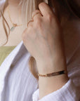 Model wearing 14k gold fill Alexandra Name Plate Bracelet. This Bracelet features a simple hammered Name plate that you get to customize with any character of your choice with 8 initials. The plate is connected by the Alexandra chain.