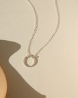 sterling silver spiral circle pendant on a dainty sterling silver chain in the sunlight