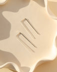 sterling silver staple earrings laid in wavy dish