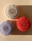 Three round fabric travel cases on a beige background.
