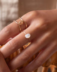 mother of pearl stone set in a bezel on a 14k gold fill skinny ring band, photographed on a model's hand