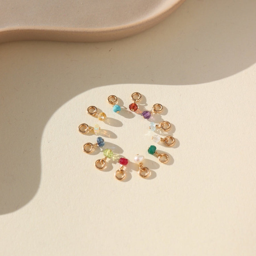 tiny birthstone gems photographed in a circle on a sunlit tabletop