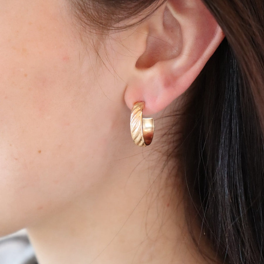 14k gold fill hoop earrings featuring a wave texture, photographed on a brunette model