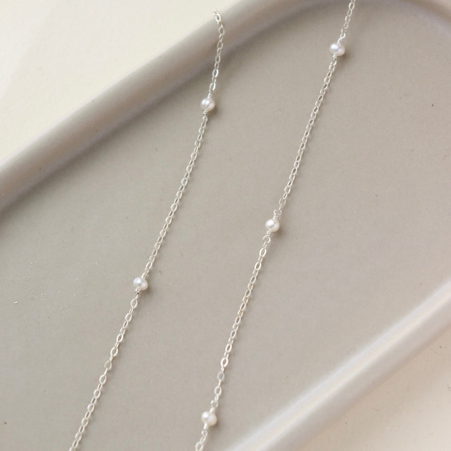 dainty pearls on a sterling silver chain photographed on a ceramic dish