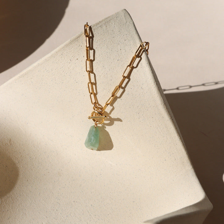 14k gold fill chain necklace with a toggle clasp that has an aquamarine stone on alight dish