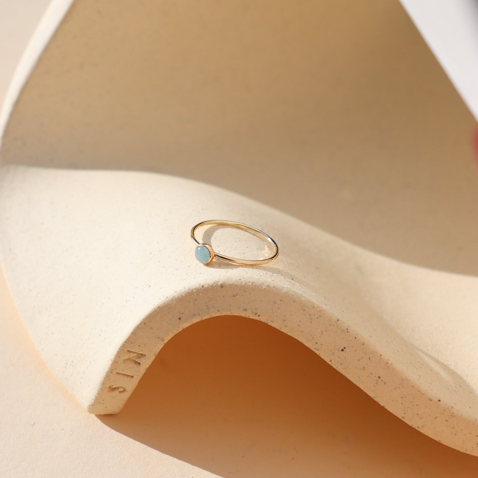 14k gold fill bezel ring setting with 4mm aquamarine stone on a light dish