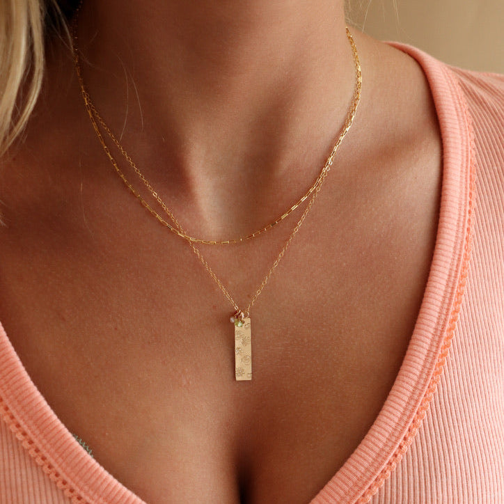 model wearing 14k gold fill delicate chain necklace with hand stamped birth flowers on a bar pendant