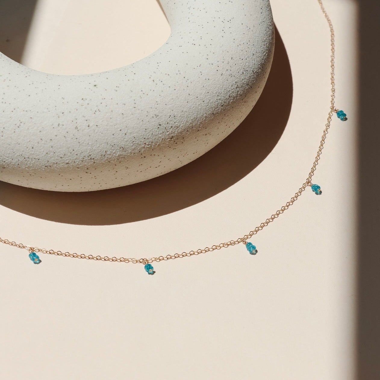 14k gold fill delicate chain necklace with gemstone charms in the sunlight