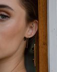 Model wearing 14k gold fill Staple Earring. A minimal earring that's perfect for everyday. Wear them in your second ear holes or let them be the main adornment for your ear lobes! Either way, these earrings will become one of your daily staples (pun, intended!).