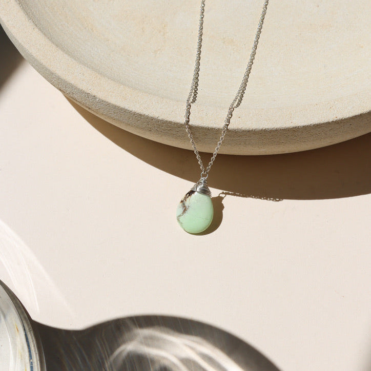 sterling silver chain necklace with wire wrapped lemon chrysoprase stone on a light dish