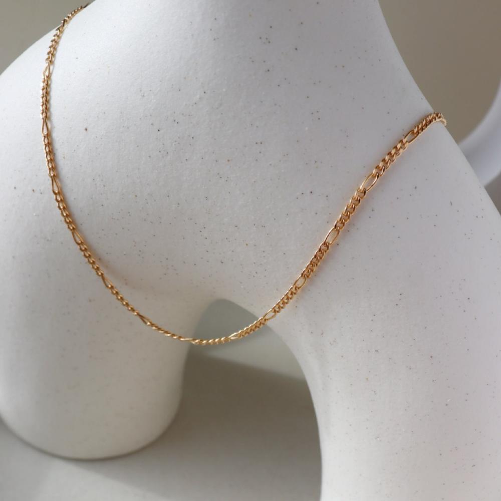 14k gold fill figaro chain on a white vase