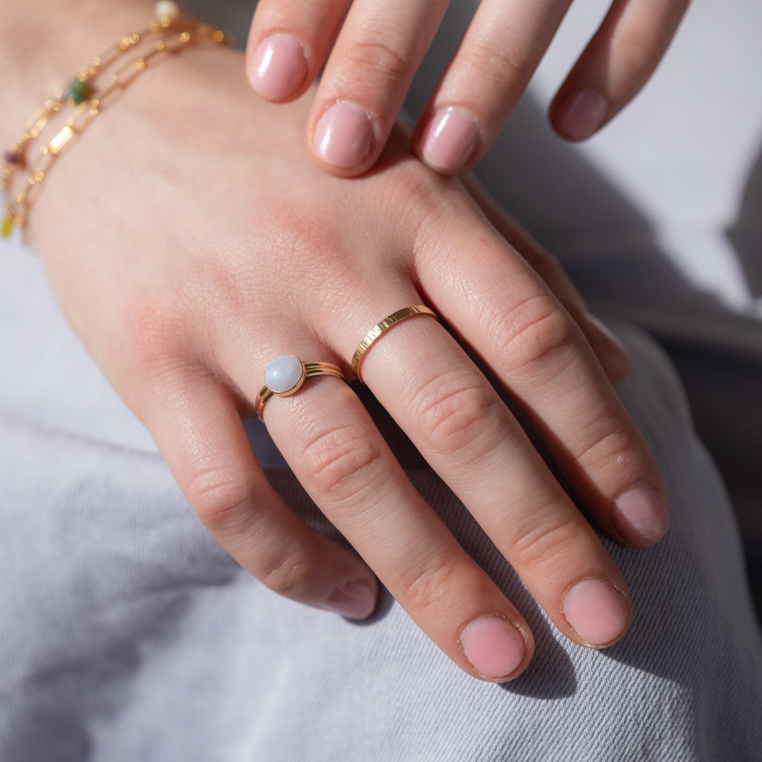 model wearing 14k gold fill ring with blue lace agate stone paired with other 14k gold fill rings