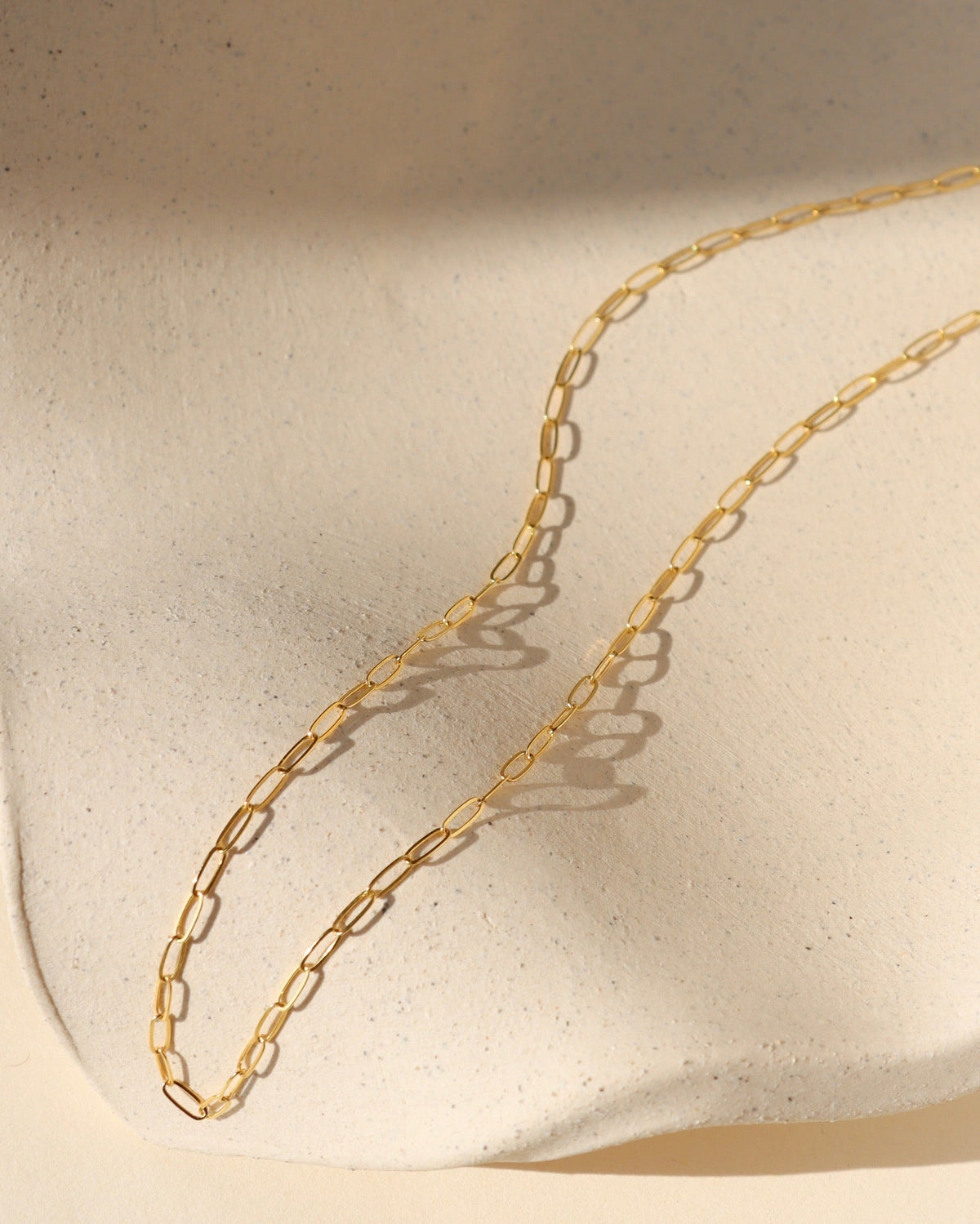 14k gold fill delicate cosette chain on wavy dish in the sunlight