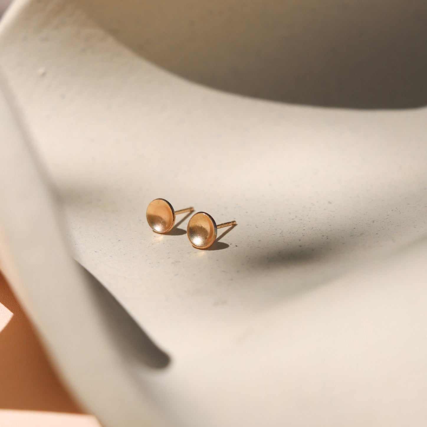 14k gold fill domed circle studs on a light dish