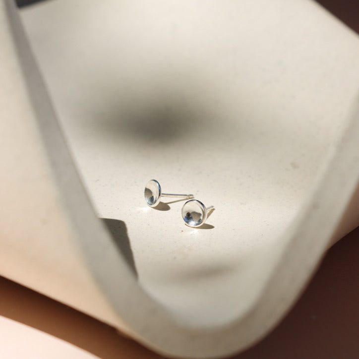 sterling silver domed circle studs on a light dish