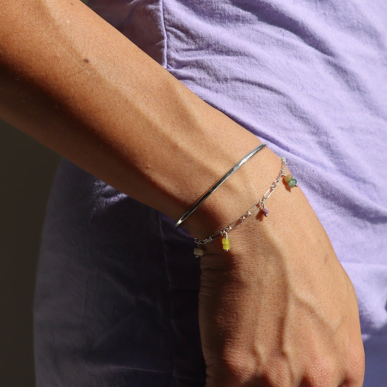model wearing sterling silver charm bracelet paired with other sterling silver jewelry