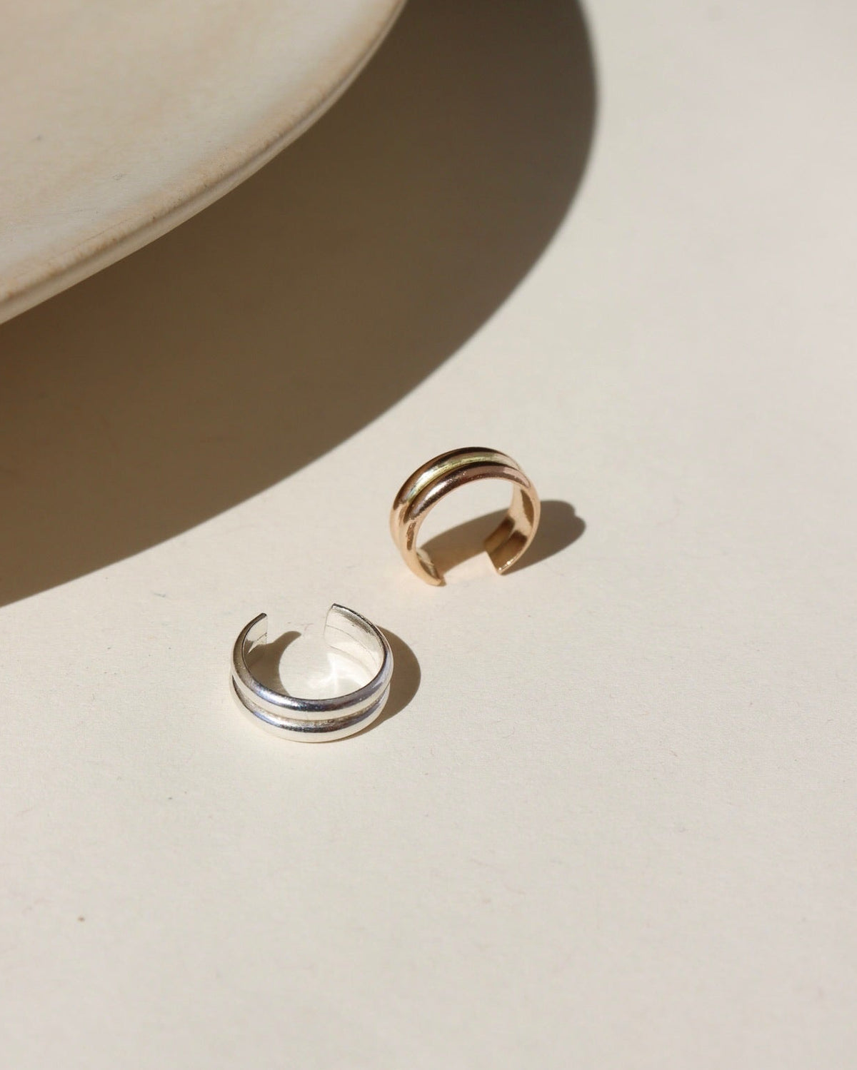A 14k gold fill + sterling silver doubled layered ear cuff, displayed on a cream backdrop in the sunlight