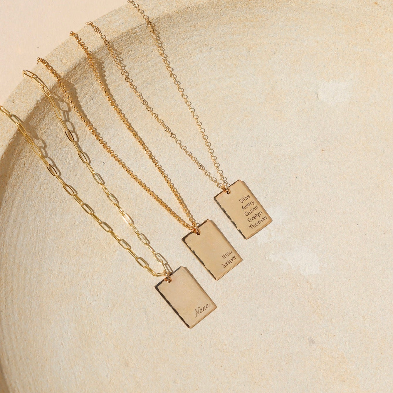 14k gold fill engraved pendants on chain necklaces on a light dish