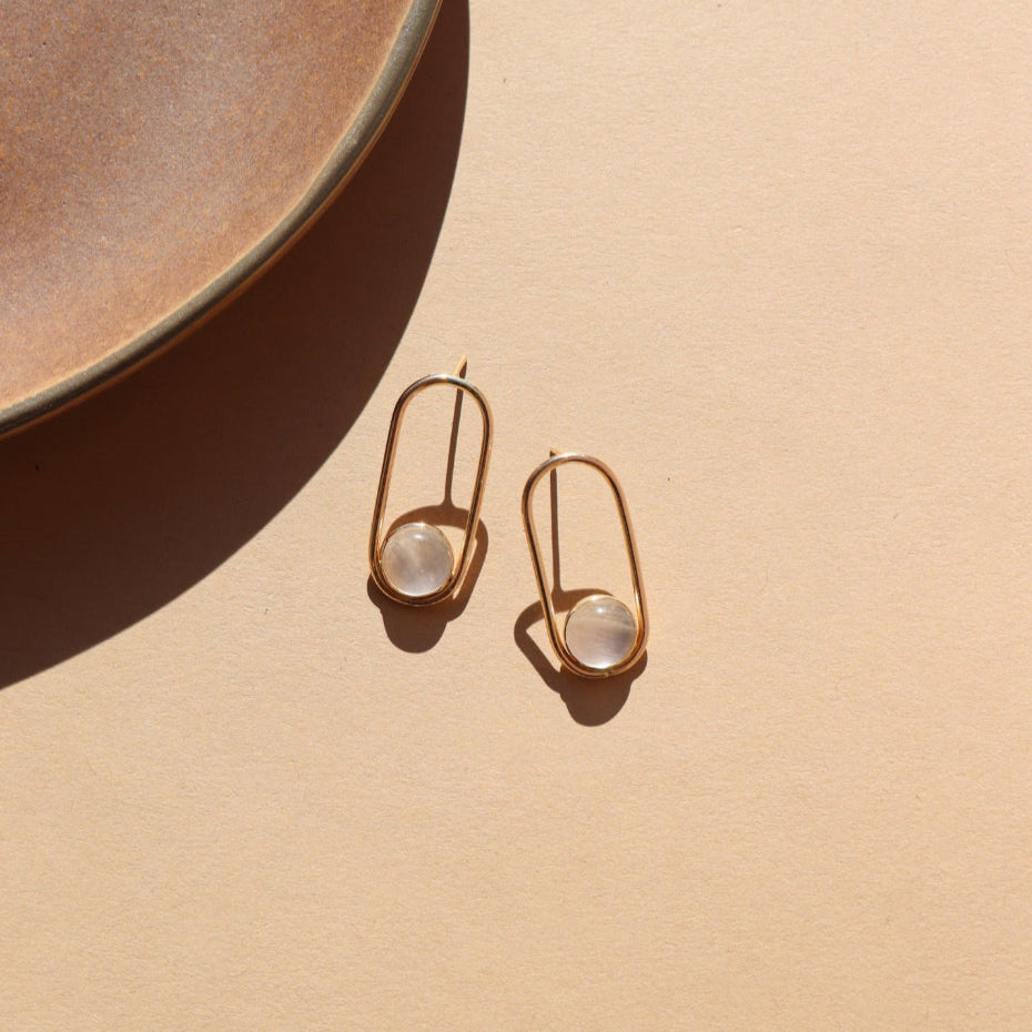 A post earring with 14k gold fill wire earring with a 8mm moonstone gemstone. The earrings are displayed on a cream back drop. 