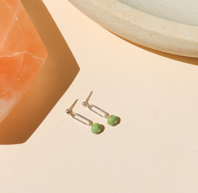 sterling silver stud earrings with turquoise bead drops on a light dish