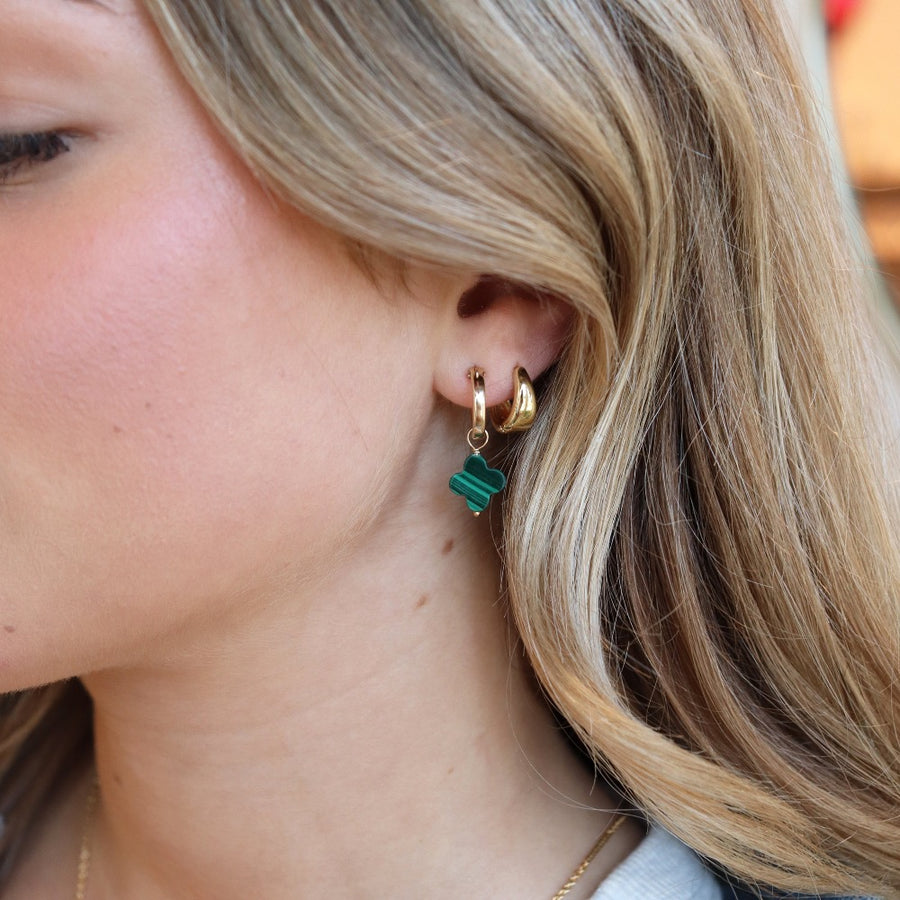 small 14k gold fill hoop earrings featuring a dangling clover shaped malachite stone, photographed on a blonde model