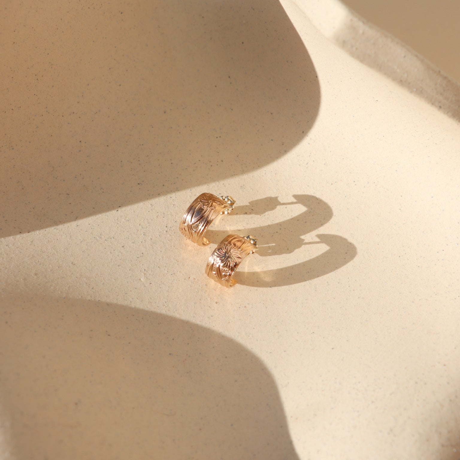 Close-up of Florence gold fill huggie  earrings featuring a floral design