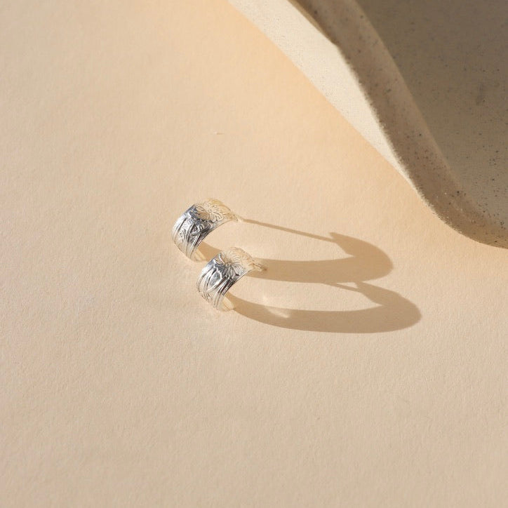 Close-up of Florence sterling silver huggie  earrings featuring a floral design