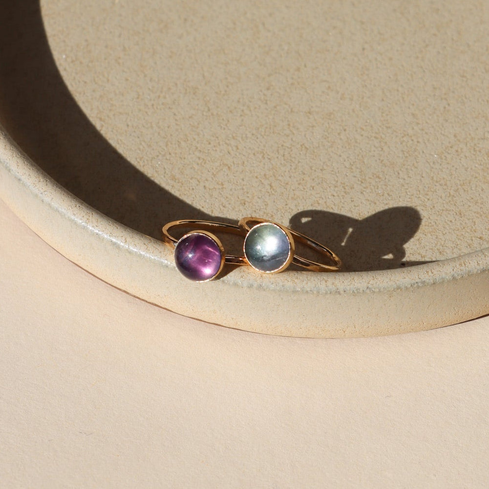 2 14k gold fill rings with round fluorite stones on a light dish