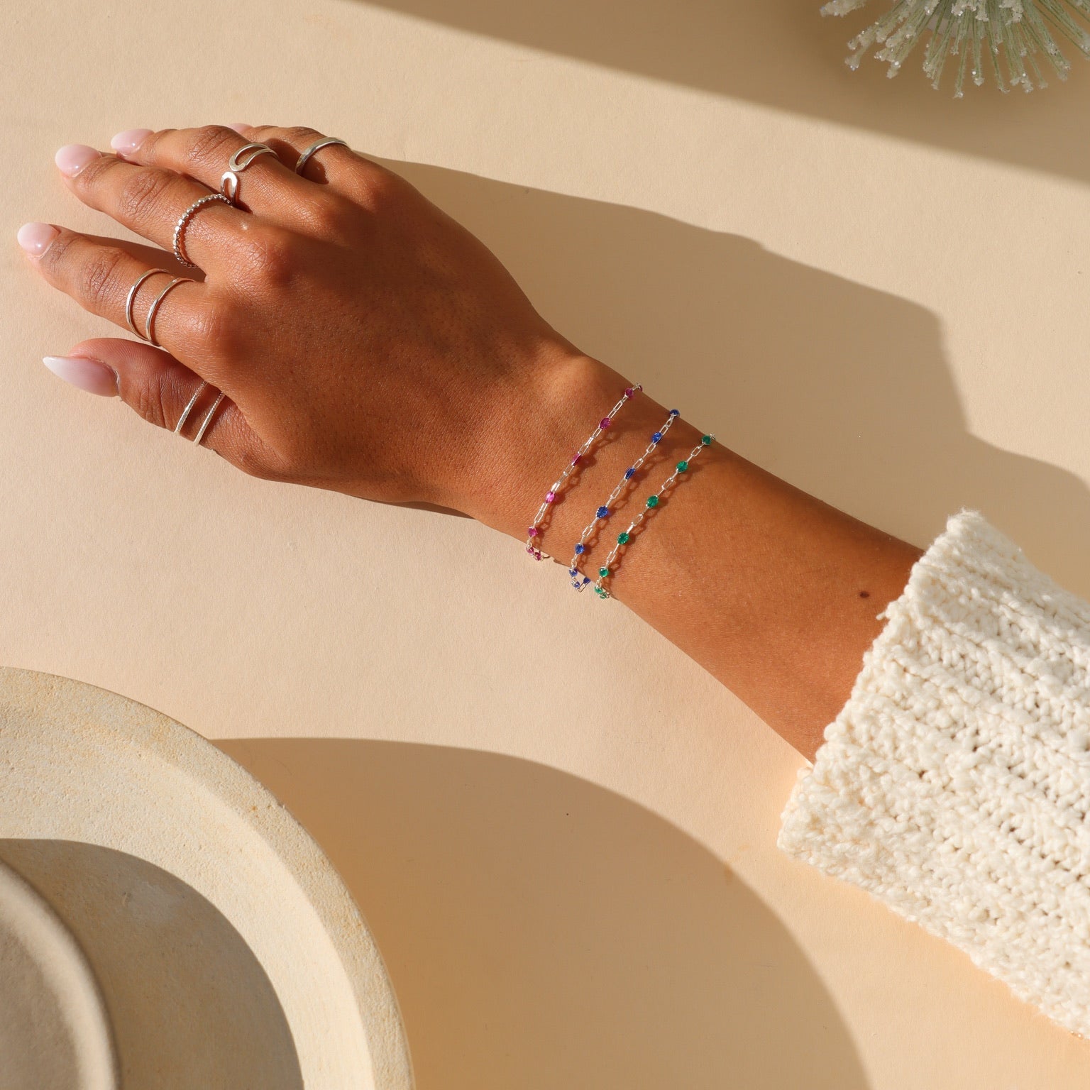 model wearing ruby gemlink bracelet in sterling silver paired with other bracelets in the sunlight
