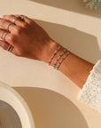model wearing ruby gemlink bracelet in sterling silver paired with other bracelets in the sunlight