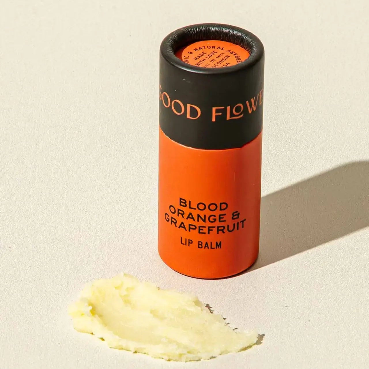 Lip balm container labeled 'Blood Orange & Grapefruit' on a beige background